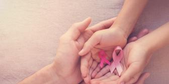 Hände von Mutter und Tochter, die rosa Schleifen halten